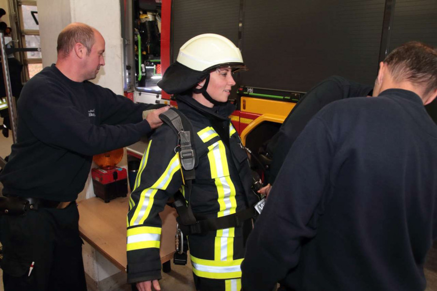 Feuerwehrbeamte helfen Deborah Steffens dabei, die schwere Ausrüstung samt Sauerstoffmaske abzulegen.
